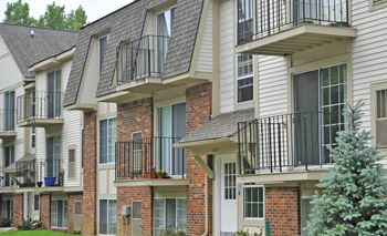 an apartment building with balconies and brick and white siding  at Fox Pointe Apartments, East Moline, Illinois